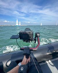 Closeup of a camera recording across open water from a boat.