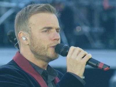 Closeup of Gary Barlow singing into a microphone on stage.