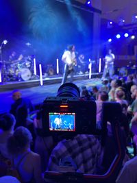 Closeup of a camera recording a saxophonist on stage.