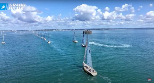 Drone shot of a series of ships travelling towards the shore.