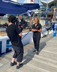 A camera operator filming an interviewee on a harbour.